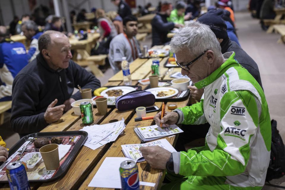 In this Sunday, Jan. 12, 2020 photo, co-driver Maurizio Dominella of Italy, checks the road book for the next stage at the restaurant of the Dakar Rally in Wadi Al Dawasir, Saudi Arabia. Formerly known as the Paris-Dakar Rally, the race was created by Thierry Sabine after he got lost in the Libyan desert in 1977. Until 2008, the rallies raced across Africa, but threats in Mauritania led organizers to cancel that year's event and move it to South America. It has now shifted to Saudi Arabia. The race started on Jan. 5 with 560 drivers and co-drivers, some on motorbikes, others in cars or in trucks. Only 41 are taking part in the Original category. (AP Photo/Bernat Armangue)