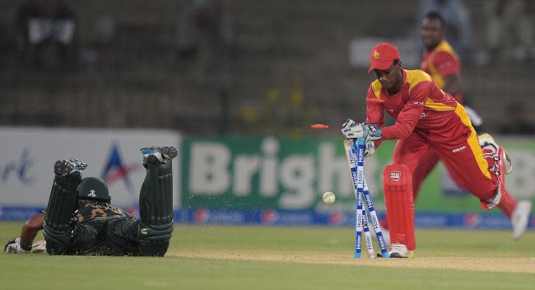 Zimbabwe's wicketkeeper Richmond Mutumbami (R) makes an unsuccessful attempt to run out Pakistan's Asad Shafiq during the second One Day International cricket match in Lahore on May 29, 2015