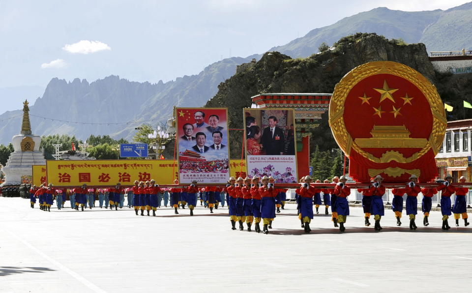 Performers carry a giant Chinese national emblem (R) and pictures of Chinese government leaders including President Xi Jinping, former country leaders Hu Jintao, Jiang Zemin, Deng Xiaoping and Mao Zedong, during the celebration event at the Potala Palace marking the 50th anniversary of the founding of the Tibet Autonomous Region, in Lhasa, Tibet Autonomous Region, China, September 8, 2015. REUTERS/China Daily CHINA OUT. NO COMMERCIAL OR EDITORIAL SALES IN CHINA