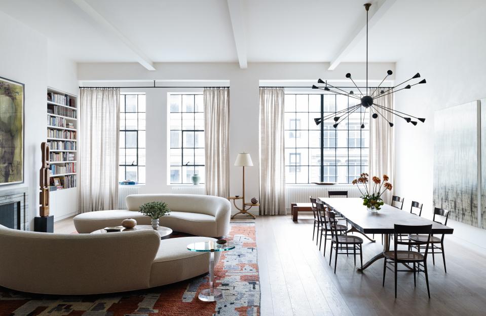 The open space at the front of designer Laura Santos's SoHo loft comprises two Cloud sofas by Vladimir Kagan from Ralph Pucci. The coffee table is by Ado Chale, designed in Belgium in 1970 and purchased from Van den Akker Antiques. The side table is by Les Prismatiques, designed in France in the 1960s and purchased from Wyeth. The standing sculpture is attributed to Leo Amino and designed in 1950 and also purchased from Wyeth. The floor lamp is French, 1940s and from the Wooster Gallery, while the rug is from Woven Accents. The loft’s drapes are custom, with material from Calvin Fabrics.