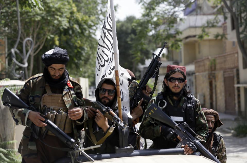 Taliban fighters display their flag while holding weapons in Kabul. Source: AP Photo/Rahmat Gul