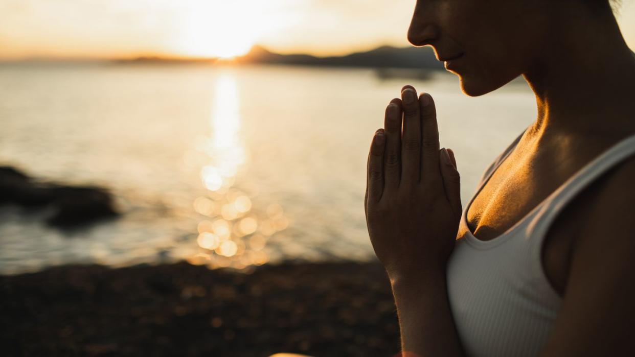 a woman with prayer hands practicing yoga and meditation
