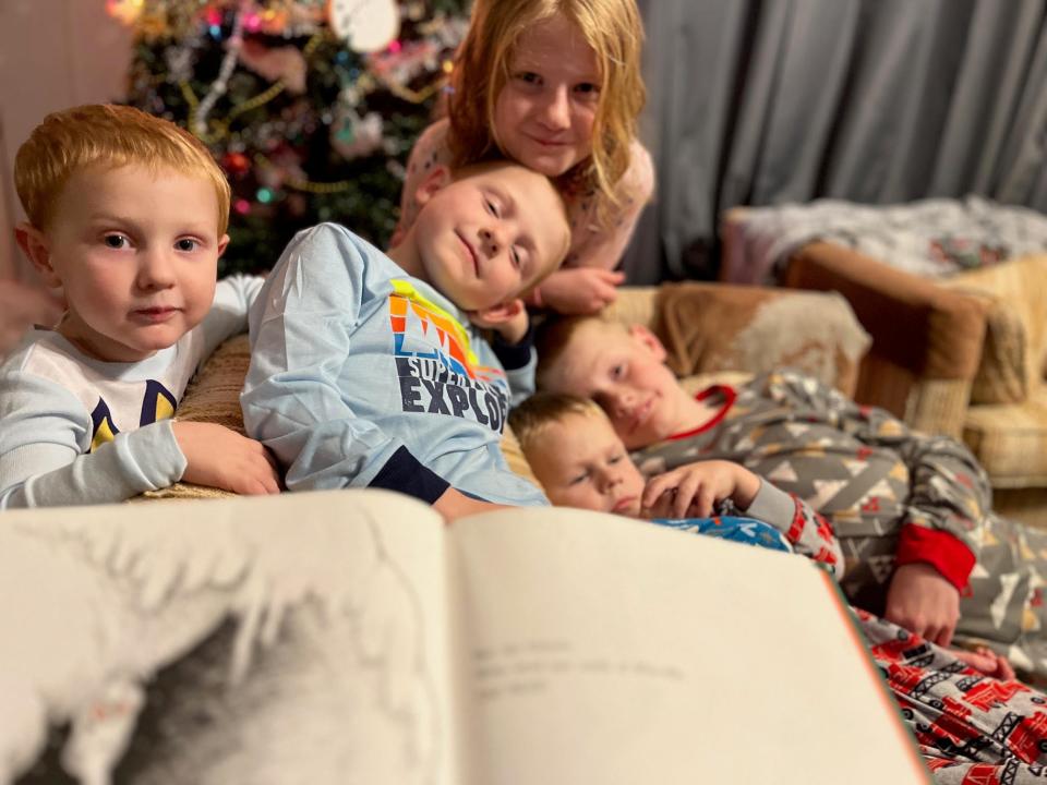 lisa's kids curled up on a couch listening to her read a story