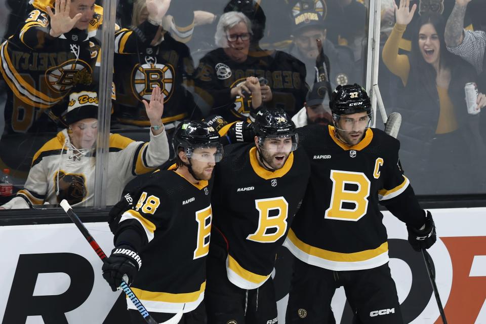 Boston Bruins' Jake DeBrusk (74) celebrates his goal with teammates Matt Grzelcyk (48) and Patrice Bergeron (37) during the first period of an NHL hockey game against the Ottawa Senators, Monday, Feb. 20, 2023, in Boston. (AP Photo/Michael Dwyer)