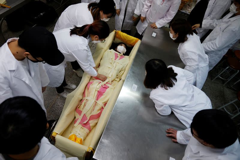 Park Se-jung who majors the funeral directing at Eulji University, is laid in a mock coffin during a class on how to shroud the deceased, in Seongnam