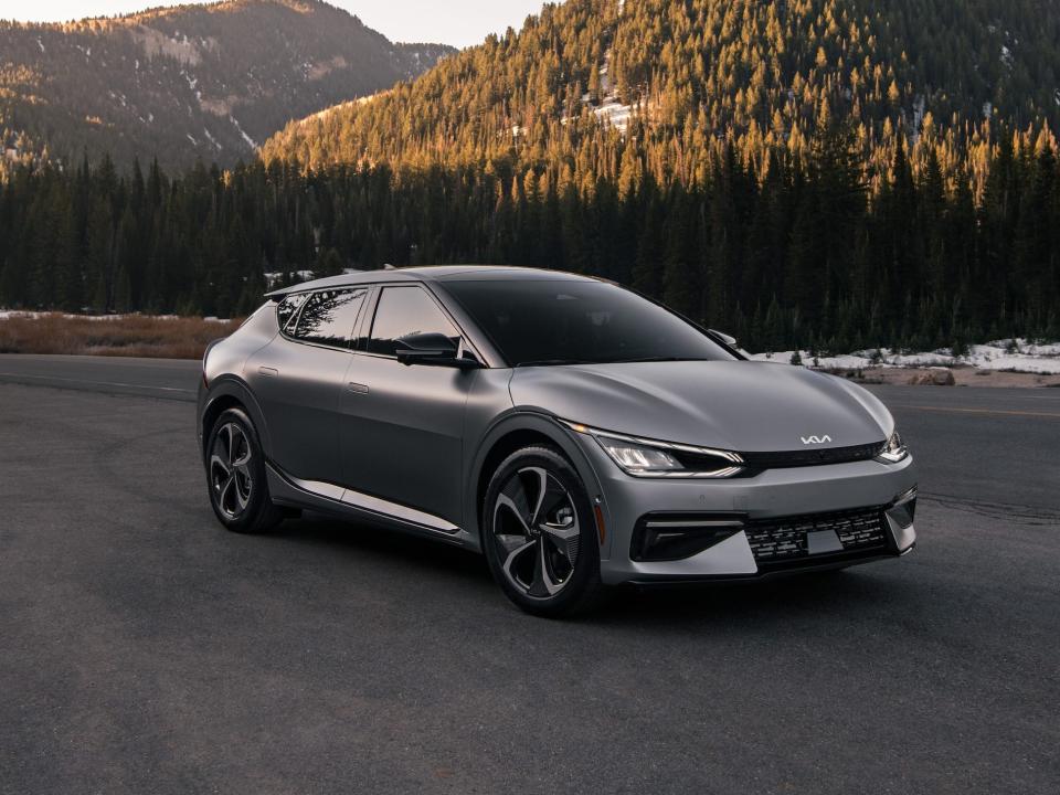 An electric car on a road with trees and mountains in the background.