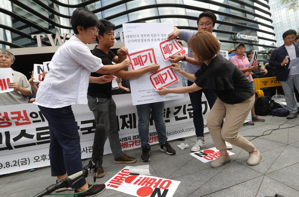 South Korean protesters attach stickers on a board symbolizing the General Security of Military Information Agreement between South Korea and Japan during a rally against Japan in front of a building which houses Japanese embassy in Seoul, South Korea, Friday, Aug. 2, 2019. Japan's Cabinet on Friday approved the removal of South Korea from a "whitelist" of countries with preferential trade status, a move sure to fuel antagonism already at a boiling point over recent export controls and the issue of compensation for wartime Korean laborers. The signs read: "Scrap."(AP Photo/Ahn Young-joon)