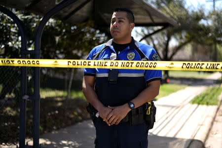 A police officer stands guard by crime scene tape at the home where a 17-year-old boy was killed and a woman injured in a package bomb explosion in Austin, Texas, U.S., March 12, 2018. REUTERS/Sergio Flores