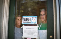 Steve, right, and Chris Brophy, husband and wife owners of Brickley's Ice Cream, look out from the store they closed after teenage workers were harassed by customers who refused to wear a mask or socially distance, in Wakefield, R.I., Wednesday, July 29, 2020. "Some of them don't believe it's real (COVID-19) and some don't think it's a big deal, I do," Steve Brophy said, adding that he would rather close than put young workers and customers at risk of harassment, and the virus. "It's like it's OK to be a jerk in this environment." (AP Photo/David Goldman)