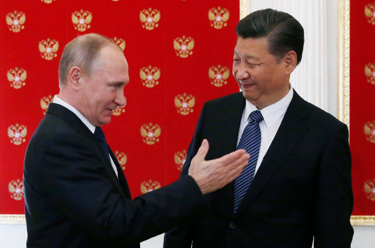 Russian President Vladimir Putin (L) gestures as he welcomes China's President Xi Jinping during an informal meeting in the Kremlin in Moscow on July 3, 2017.