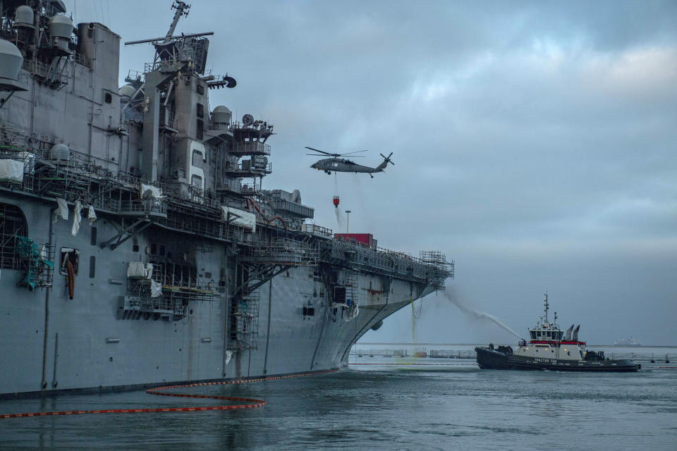 An MH-60S Sea Hawk helicopter from Helicopter Sea Combat Squadron (HSC) 3 combats a fire aboard the amphibious assault ship USS Bonhomme Richard (LHD 6) at Naval Base San Diego on Tuesday, July 14, 2020, as the ship endures an ongoing fire. A Navy statement says there's been significant progress and much less smoke is being emitted from the USS Bonhomme Richard on Tuesday. (Mass Communications Specialist 3rd Class Jason Waite/U.S. Navy via AP)