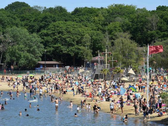 People enjoy the sunshine in the water and on the beach at Ruislip Lido in west London on Saturday (JUSTIN TALLIS/AFP via Getty Images)