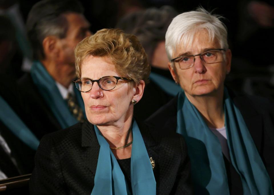 Ontario Premier Kathleen Wynne (L) and her partner June Rounthwaite sit before the state funeral for Canada's former finance minister Jim Flaherty in Toronto, April 16, 2014.