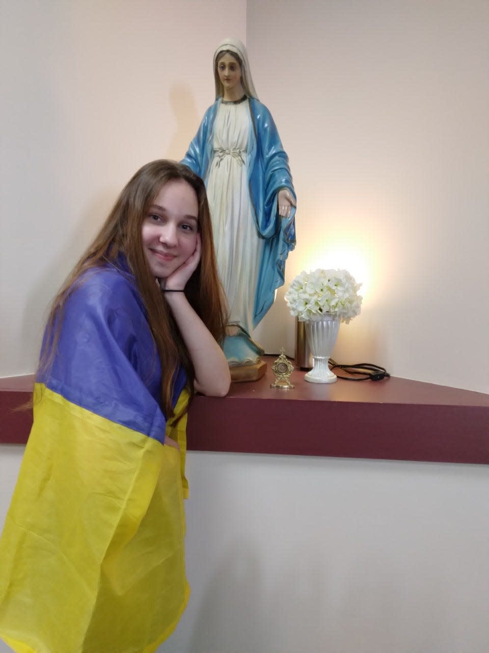 Ukrainian exchange student Anastasia Didenko stands with a statue of the Blessed Virgin Mary at Tuscarawas Central Catholic Junior/Senior High School.