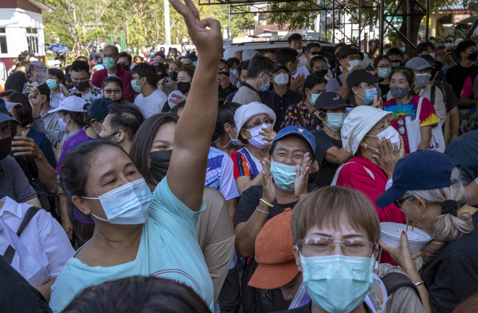 Pro-democracy protesters flash three-finger salute as their leader Arnon Nampha speaks from a makeshift stage outside Bang Khen Metropolitan Police Station, Bangkok, Thailand, Monday, Dec. 21, 2020. Several leaders of protest movement report to the police station to answer the charges of defaming the Thai monarchy, the most serious of many offenses of which they stand accused during recent pro-democracy rallies. (AP Photo/Gemunu Amarasinghe)