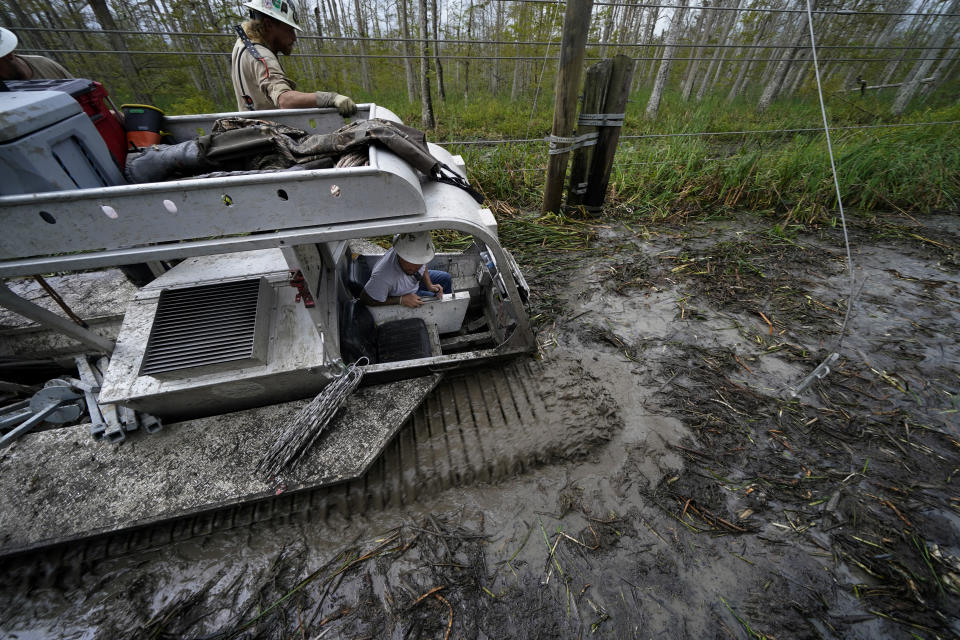 Electrical workers for Sparks Energy ride in a marsh buggy to restore power lines running through a marsh in the aftermath of Hurricane Ida in Houma, La., Friday, Sept. 17, 2021. The Louisiana terrain presents special challenges. In some areas, lines thread through thick swamps that can be accessed only by air boat or marsh buggy, which looks like a cross between a tank and a pontoon boat. Workers don waders to climb into muddy, chest-high waters home to alligators and water moccasins. (AP Photo/Gerald Herbert)