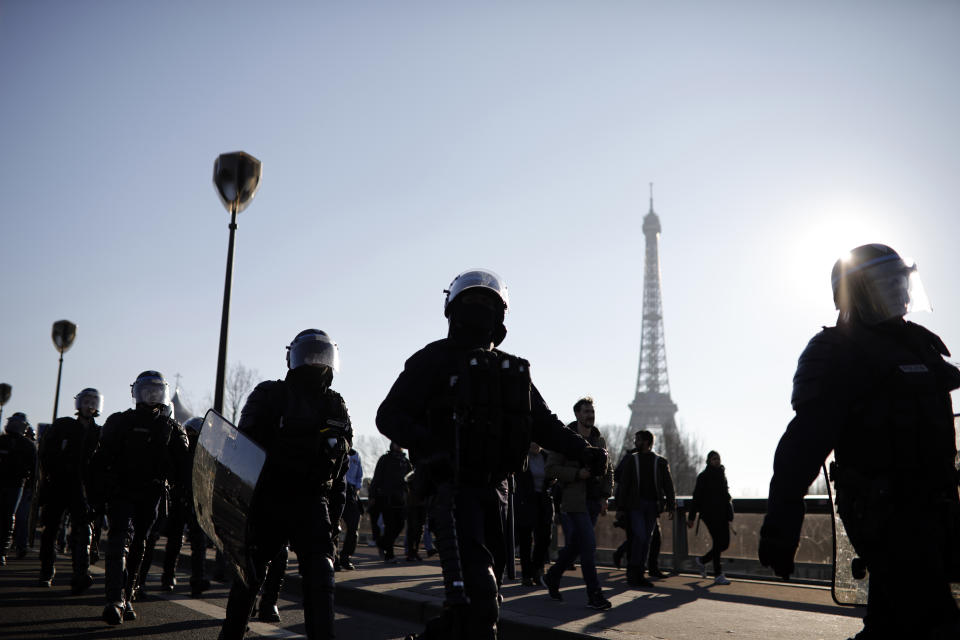 Yellow vest protesters flanked by police riot officers are silhouetted against the sun as they demonstrate in the streets of Paris, France, Saturday, Feb. 23, 2019. French yellow vest protest organizers are trying to tamp down violence and anti-Semitism in the movement's ranks as they launch a 15th straight weekend of demonstrations. (AP Photo/Kamil Zihnioglu)