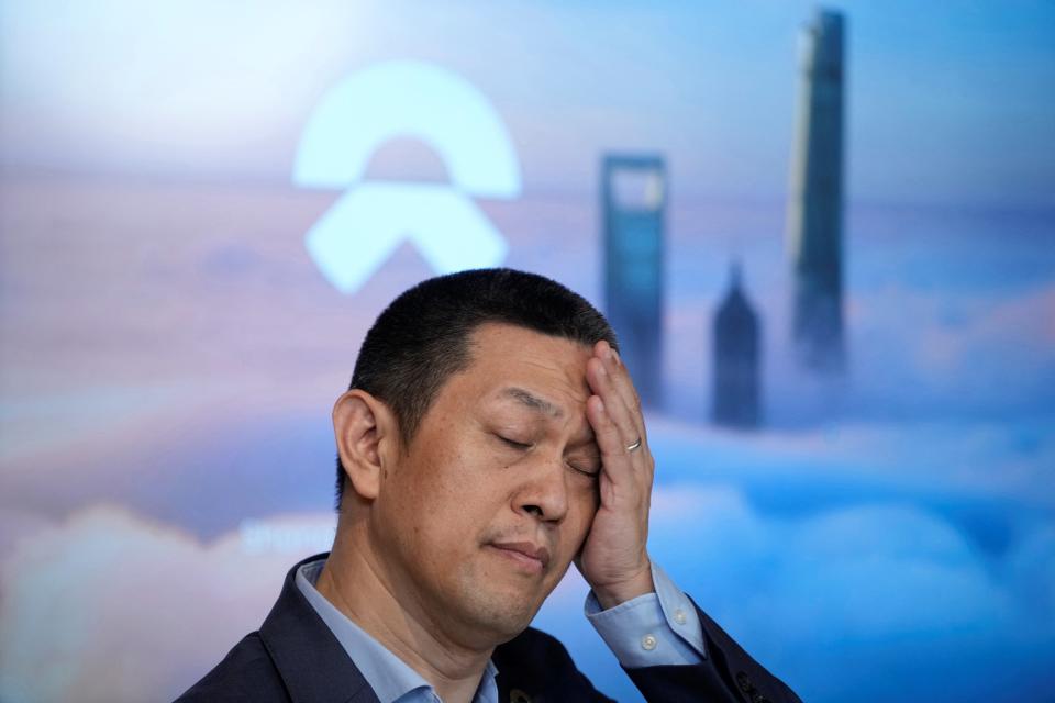 Nio CEO, William Li with his hand on his head in front of the NIO logo