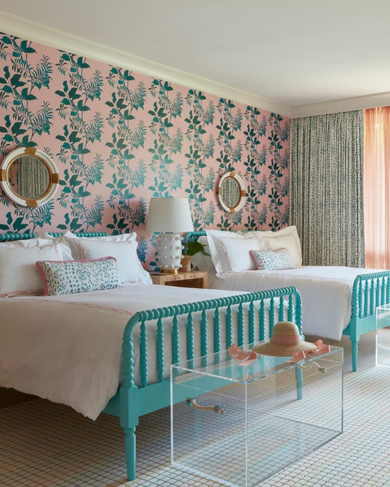 Pink and green floral motif wallpaper in bedroom with matching beds.