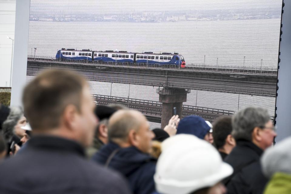 People watch a giant TV screen with Russian President Vladimir Putin, inside, riding a train across a bridge linking Russia and the Crimean peninsula in Taman, Russia, Monday, Dec. 23, 2019. Putin on Monday inaugurated a railway bridge to Crimea, the longest in Europe, which is intended to facilitate links with Crimea, which Russia annexed from Ukraine in 2014. (AP Photo)