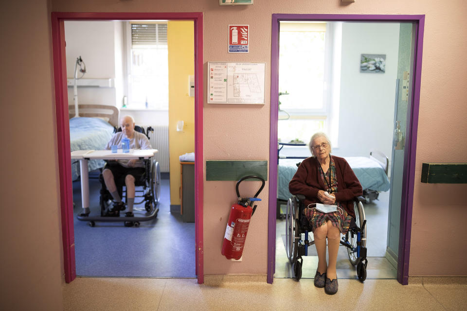 FILE - In this April 16, 2020 file photo, Marie Lithard, right, and her neighboor Yves Chretien sit looking out of their rooms in a nursing home in Ammerschwir, France. The French government announced Saturday Dec. 12, 2020, it is giving care home residents more freedom for the end of year holidays, allowing them out to spend time with their families and receive visits even if they are positive for COVID-19. (AP Photo/Jean-Francois Badias, File)