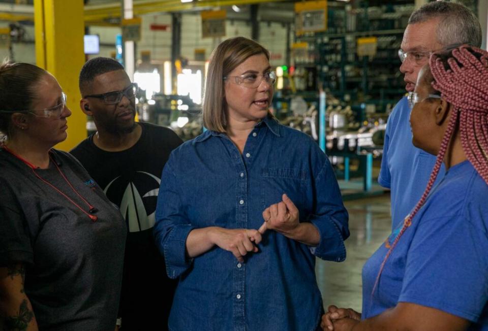 Foto de campaña electoral de la actriz estadounidense Elissa Slotkin.  Está en una fábrica, con gafas protectoras, y habla con varios trabajadores.
