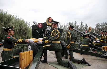 Paramilitary policemen and members of a gun salute team prepare to fire cannons during a training session for the upcoming military parade to mark the 70th anniversary of the end of the World War Two, at a military base in Beijing, China, September 1, 2015. REUTERS/Stringer