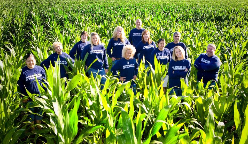 Dani Paluchniak (second from right) and employees in a cornfield. The riddle on the fronts and backs of their shirts is: &ldquo;What did the baby corn say to the mama corn? Where&rsquo;s pop corn?&rdquo; (Photo: Courtesy of Dani Paluchniak)