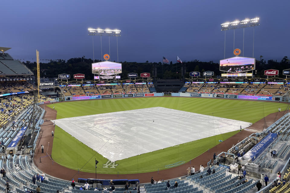 A tarp covers the field during a rain delay before a baseball game between the Los Angeles Dodgers and the San Diego Padres, Saturday, April 13, 2024, in Los Angeles. (AP Photo/Marcio Jose Sanchez)