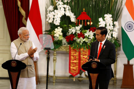 Indian Prime Minister Narendra Modi (L) applauds Indonesia President Joko Widodo after he made an address following their meeting at the presidential palace in Jakarta, Indonesia May 30, 2018. REUTERS/Darren Whiteside