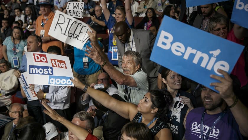 A man tries protesting with a sign that reads, "RIGGED," as delegates from Nevada cast their votes during roll call 2016 Democratic National Convention on Tuesday.