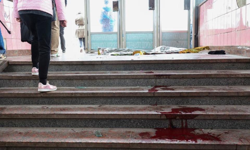 People walk past bloodstains after shelling hit Kharkiv.