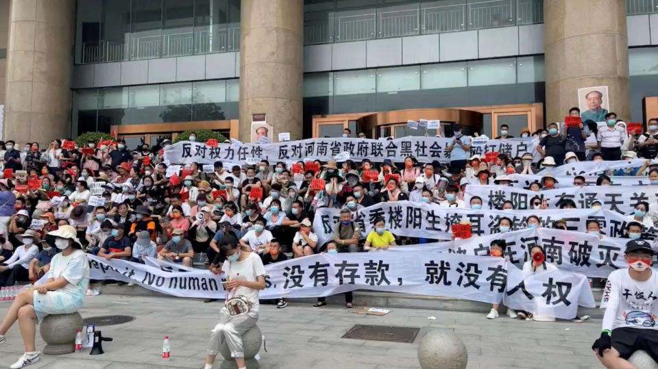 Demonstrators hold banners during a protest over the freezing of deposits by rural-based banks in China.