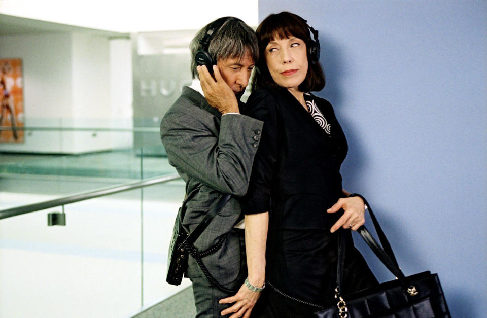 Dustin Hoffman and Lily Tomlin listen to headphones in a hallway