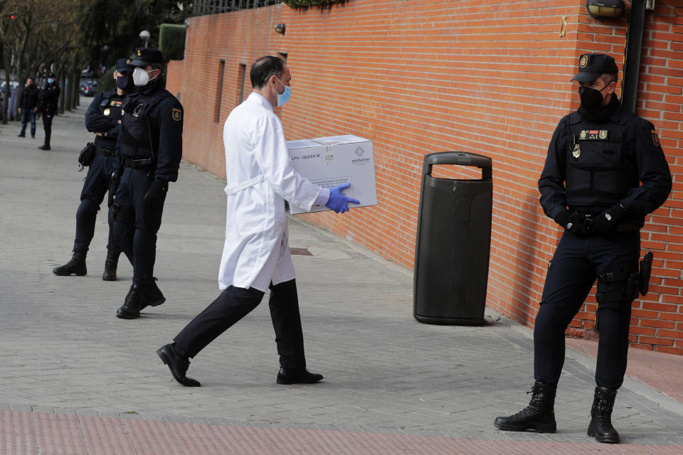 Police stand by the entrance of a nursing home as a box of some of the first Pfizer coronavirus vaccines arrives in Madrid, Spain, Sunday Dec. 27. 2020. Spain plans to receive over 4.5 million doses of the vaccine over the next three months, enough it says to immunize just over 2.2 million people. The government estimates that this first phase will be enough to cover nursing home residents and workers, followed by health workers in general and people with disabilities. (AP Photo/Paul White)