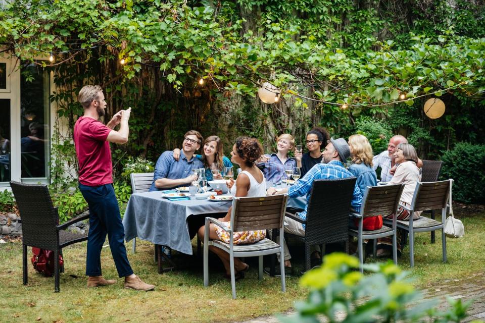 man taking photo of family having lunch outdoors