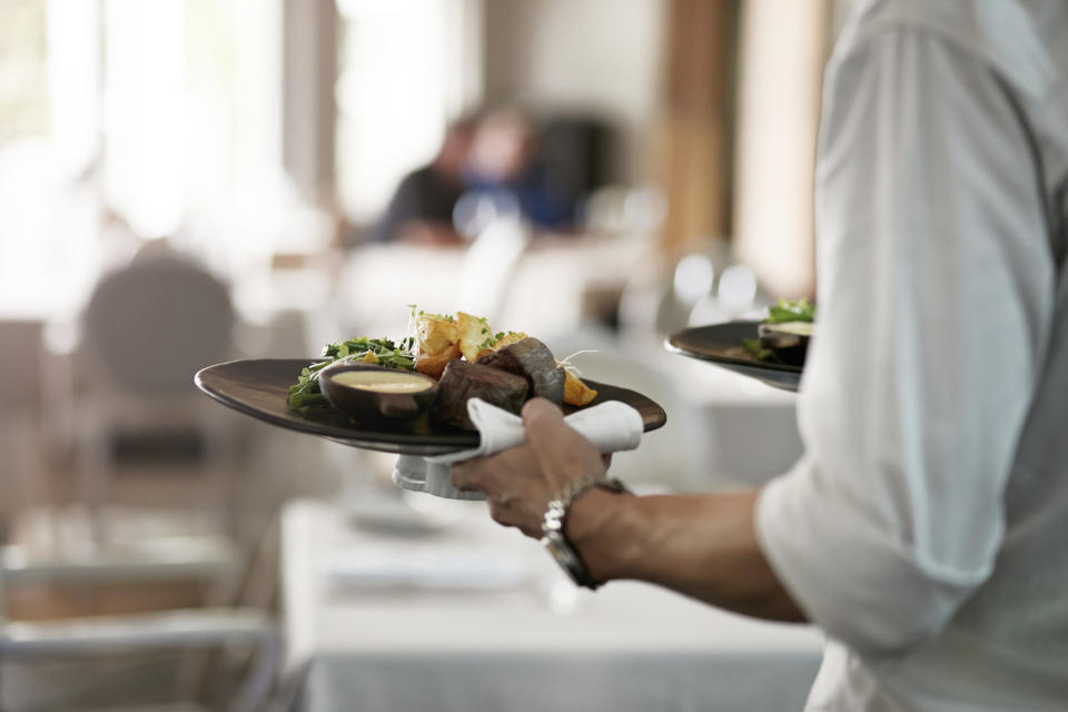 A restaurant server taking food to a table