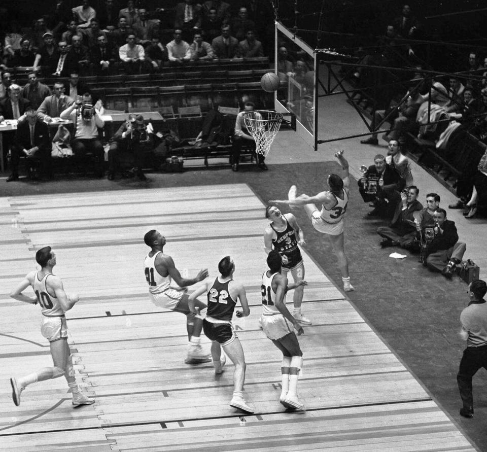 Gene Morse (33 in white, mid-air under basket), crashes to the floor after sinking a shot against Memphis State during the National Invitation Tournament final at Madison Square Garden in New York, March 23, 1957. Morse's effort contributed to Bradley's uphill 84-83 victory. In on the play were Morse's teammates Shellie McMillon (41) and Bobby Joe Mason (21).