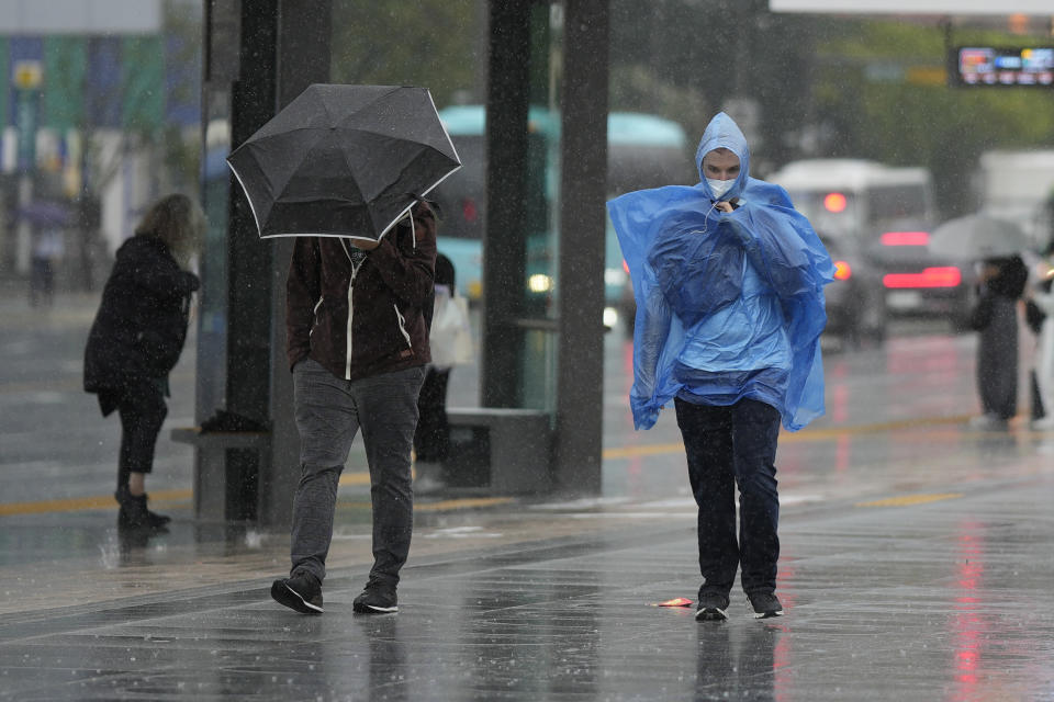 People walk in the rain as Typhoon Hinnamnor moves toward the Korean Peninsula in Seoul, South Korea, Monday, Sept. 5, 2022. Hundreds of flights were grounded and more than 200 people evacuated in South Korea on Monday as Typhoon Hinnamnor approached the country's southern region with heavy rains and winds of up to 290 kilometers (180 miles) per hour, the strongest storm in decades. (AP Photo/Lee Jin-man)