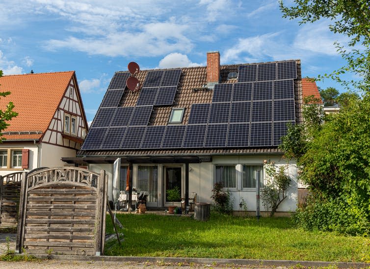 An old house with its roof covered in black solar panels