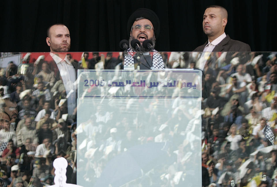 FILE - Hezbollah leader Sayyed Hassan Nasrallah, center, escorted by his bodyguard Yasser Nemr Qranbish, right, addresses supporters reflected in the bulletproof glass during the annual rally to mark Al-Quds Day, Jerusalem Day, in the southern suburbs of Beirut, Lebanon, on Oct. 28, 2005. An Israeli strike in Syria Tuesday July 9, 2024 killed Qranbish, a former personal bodyguard of Hezbollah leader, an official with the Lebanese militant group said. (AP Photo/Hussein Malla, File)