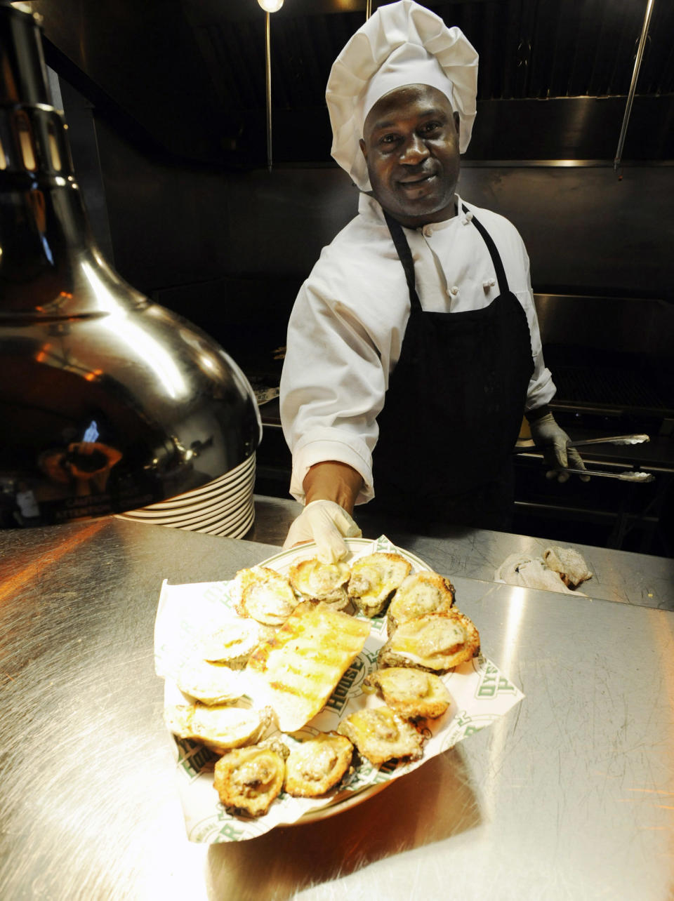 This March 1, 2014 photo shows Albert King serving a plate of grilled oysters at the Original Oyster House in Spanish Fort, Ala. The business is one of more than a half-dozen restaurants on "Seafood Row," located on a parkway across the Mobile Delta at Mobile, Ala. Many locals know the area for family-style seafood, but visitors sometimes have a difficult time finding it. (AP Photo/Jay Reeves)