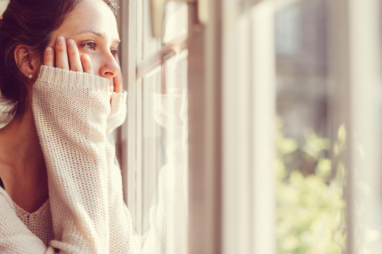 Woman looking out window, looking stressed. (Getty Images)