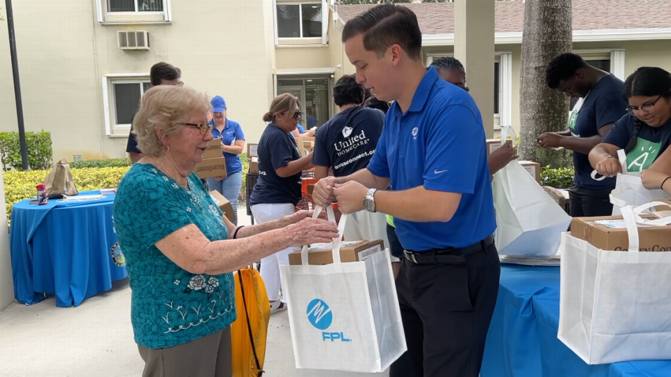 El director de Asuntos Externos de FPL Chris Ferreira entregándole un kit de comida para el huracán a una anciana del Condado Miami-Dade.