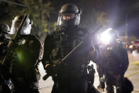 Portland police officers walk through the Laurelhurst neighborhood after dispersing protesters from the Multnomah County Sheriff's Office early in the morning on Saturday, Aug. 8, 2020 in Portland, Ore. (AP Photo/Nathan Howard)