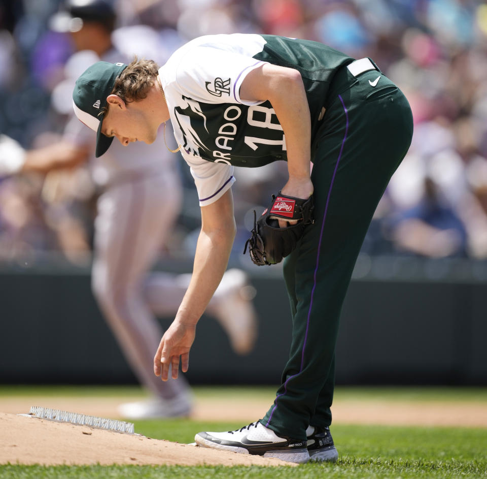 Colorado Rockies starting pitcher Ryan Feltner, foreground, reacts as Atlanta Braves' Matt Olson, background, circles the basses after hitting a three-run home run off him in the second inning of a baseball game Sunday, June 5, 2022, in Denver. (AP Photo/David Zalubowski)