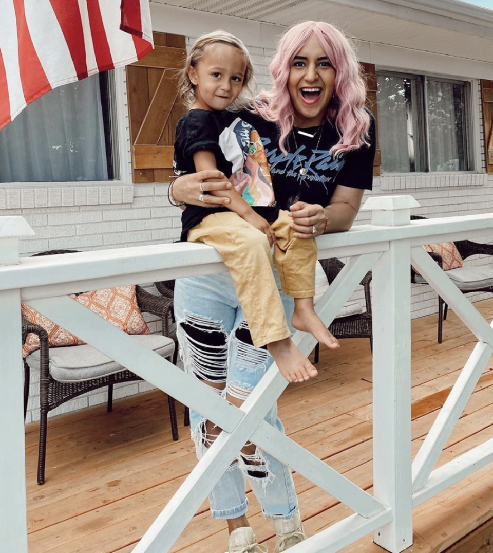 The dance teacher is seen with one of her five children while wearing a pink wig.