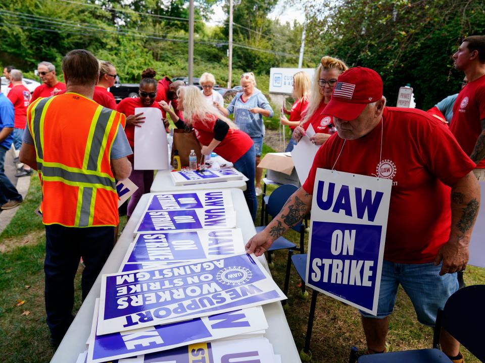 A table with signs for United Auto Workers and those supporting the union.
