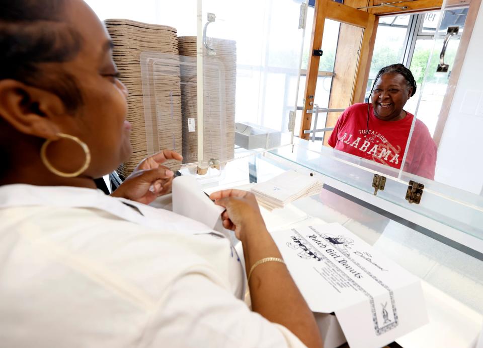 (L to R) Onica Ashley, 36, of Detroit, and a donut maker at Dutch Girl Donuts in Detroit, helps out a customer who had walked in during their soft opening on Friday, May 3, 2024.