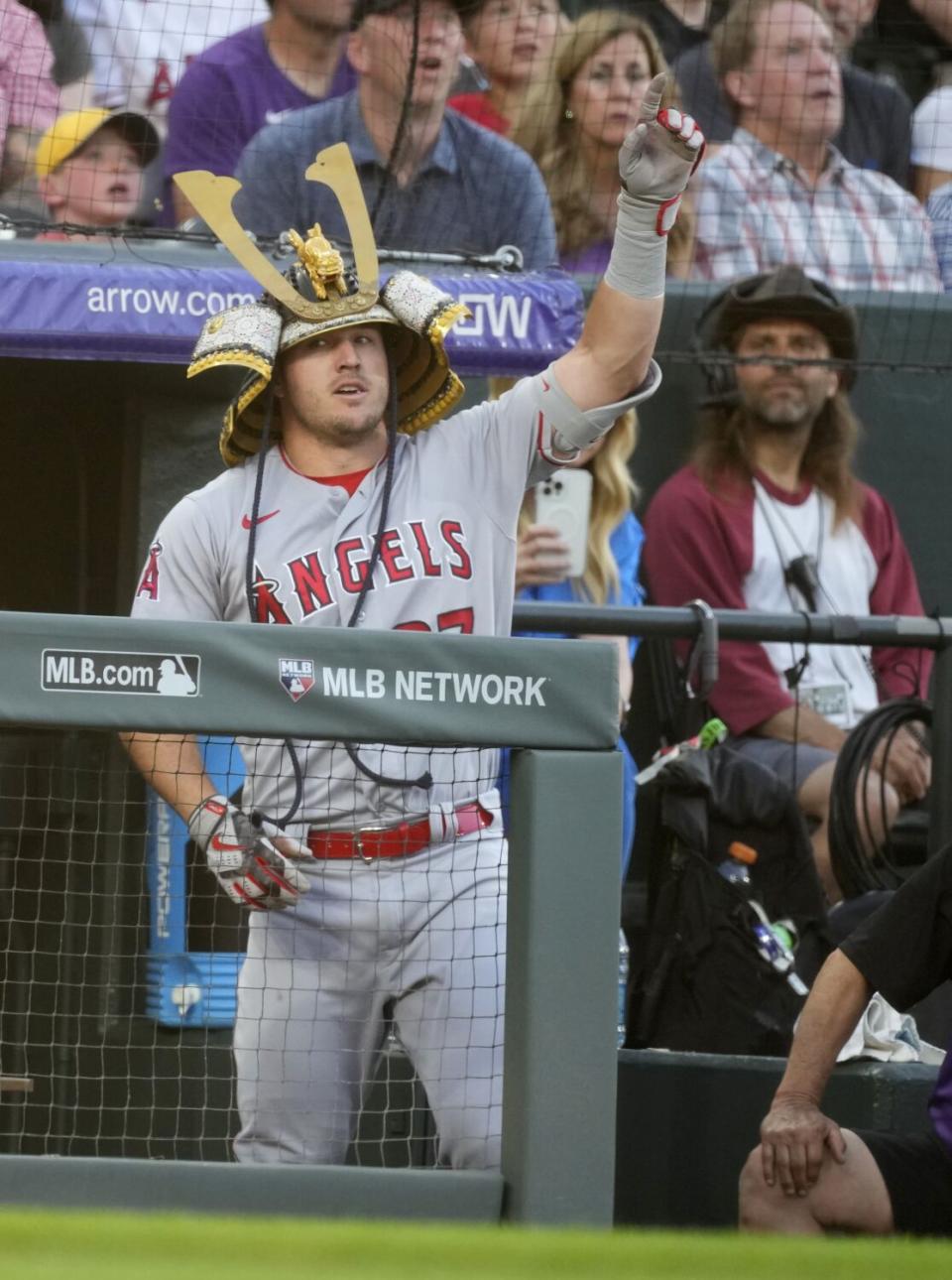 The Angels' Mike Trout points as he wears the team's home run helmet after scoring a solo shot off the Rockies